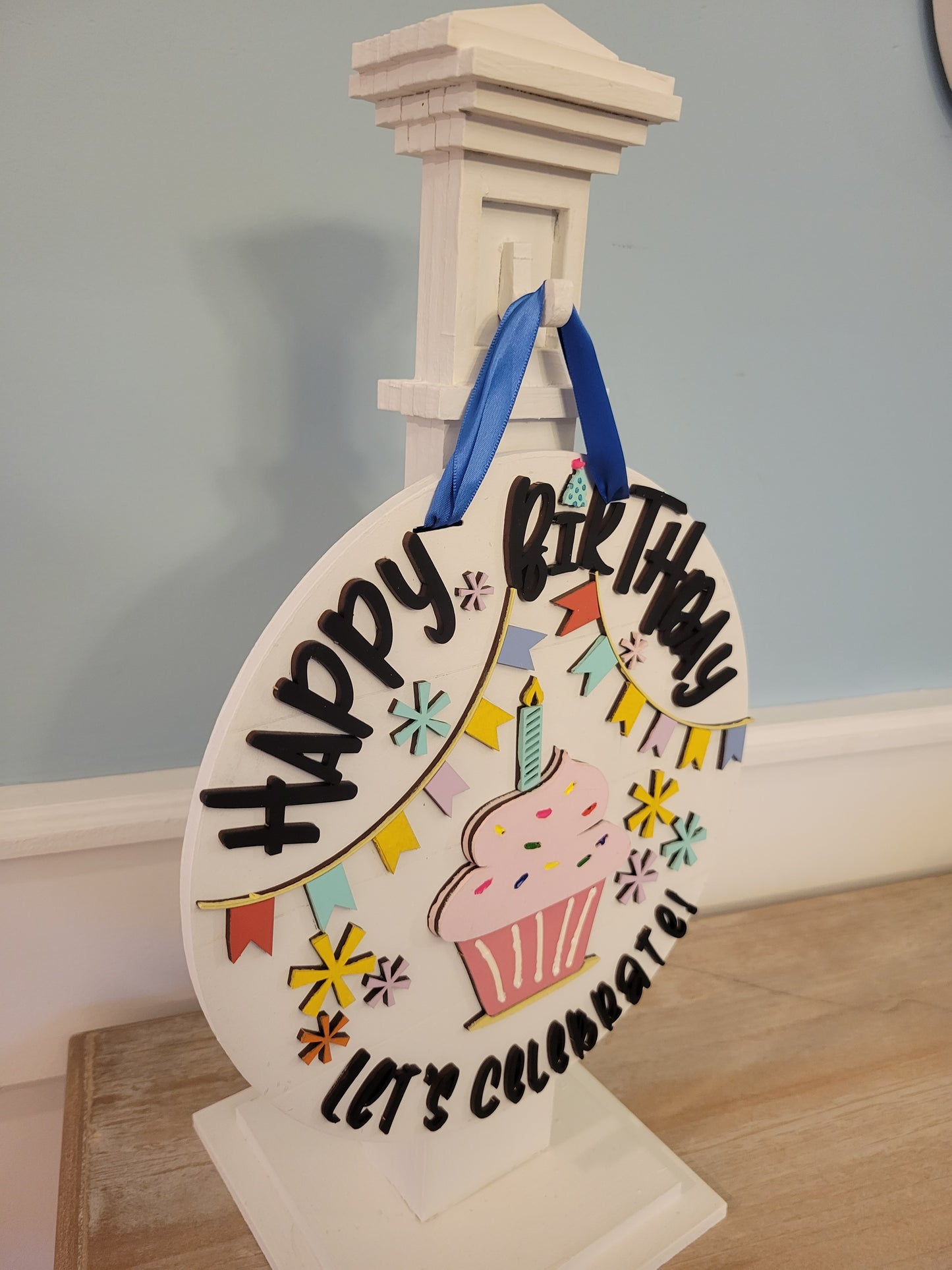 An image showcasing the 'Birthday Bliss: Festive Shelf Post Stand,' a decorative piece for home celebrations. The stand features vibrant, colorful details with interchangeable festive elements, ideal for seasonal birthday decor on shelves or tabletops. Side