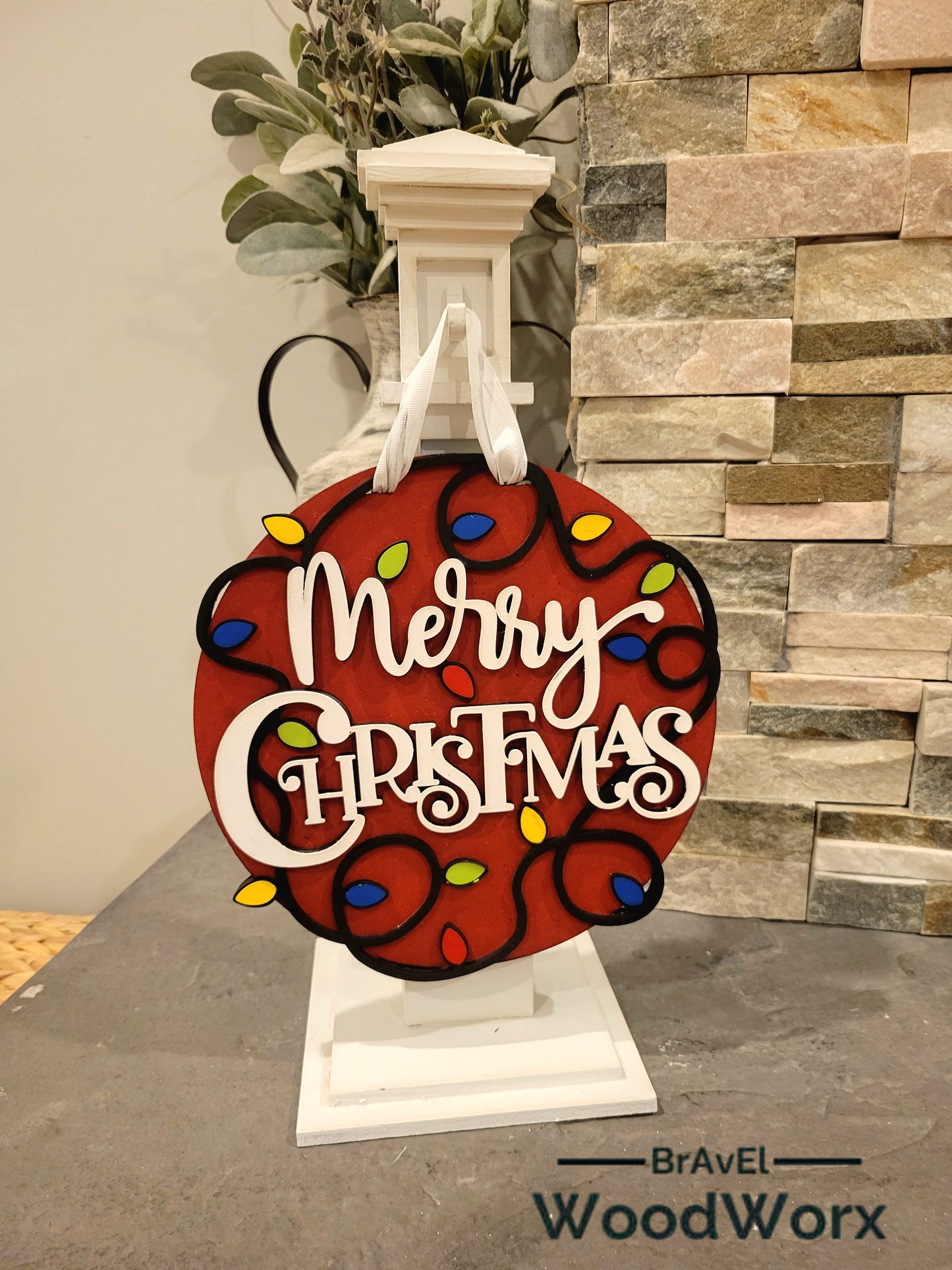 Festive red wooden door decoration with laser-cut Merry Christmas text and multicolored bulbs.