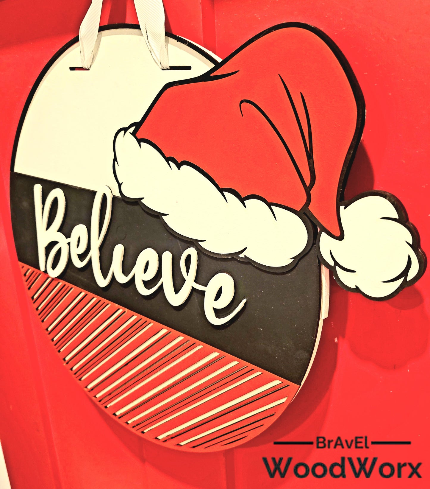 Hand-painted Christmas wall decor featuring a bold "Believe" message and red-and-white striped bottom section