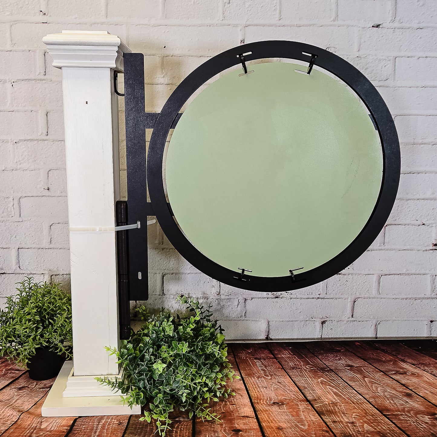 Round door with black frame and green glass on a white brick wall.