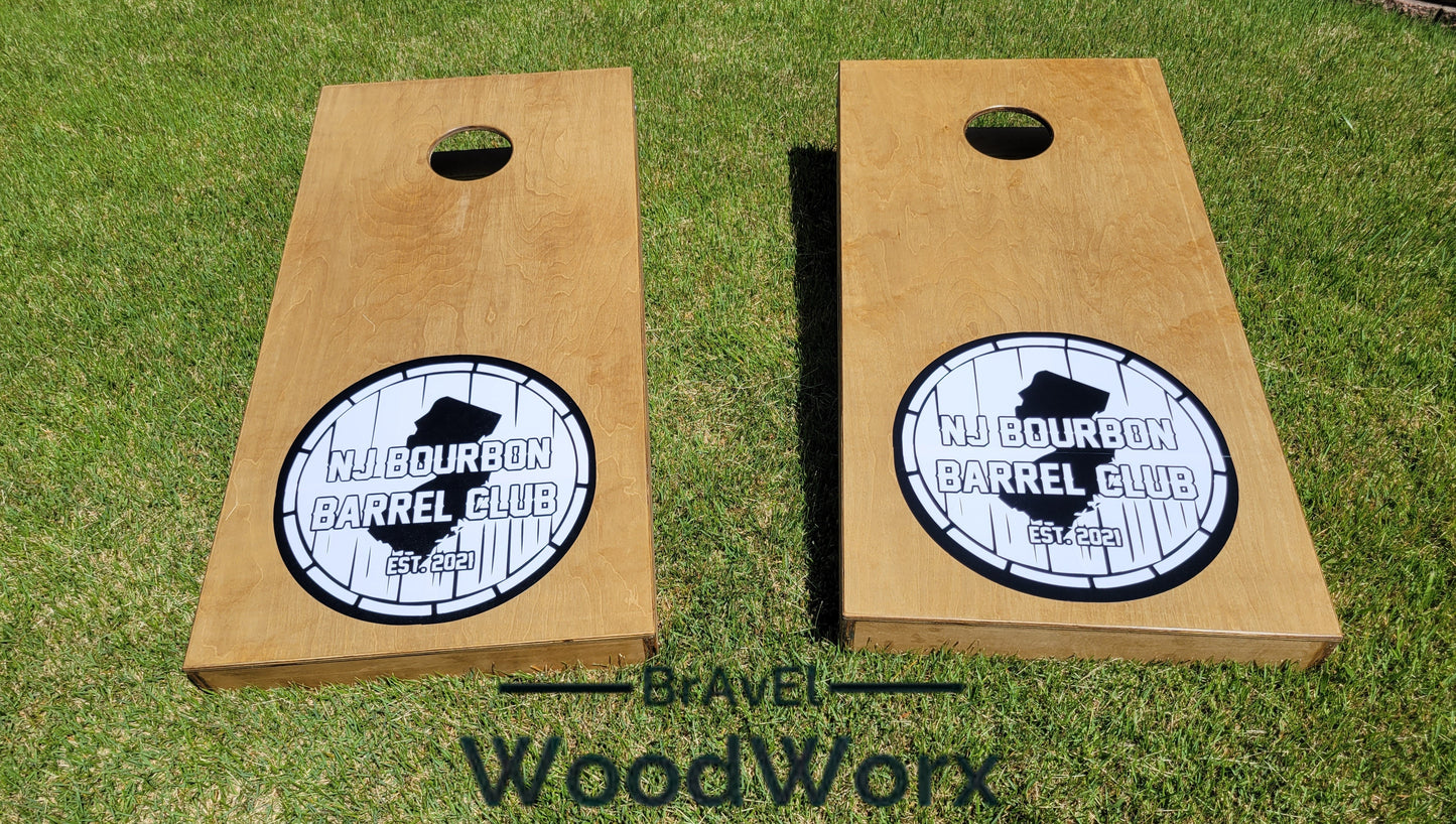 Two wooden cornhole boards with a monogram and the text 'Middourbon Barrel Club' engraved on them, placed on grass with the brand 'BrAvEl WoodWorx' visible.