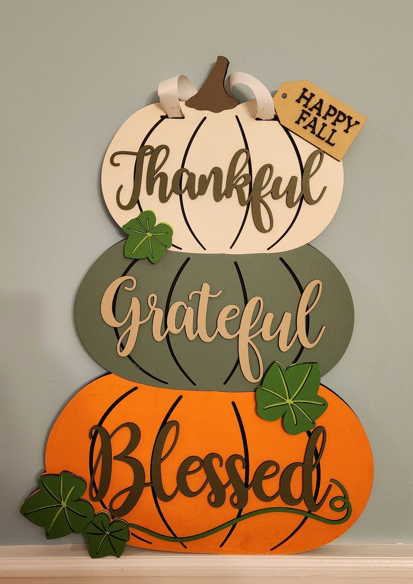 Decorative sign with pumpkins and fall phrases on a neutral background