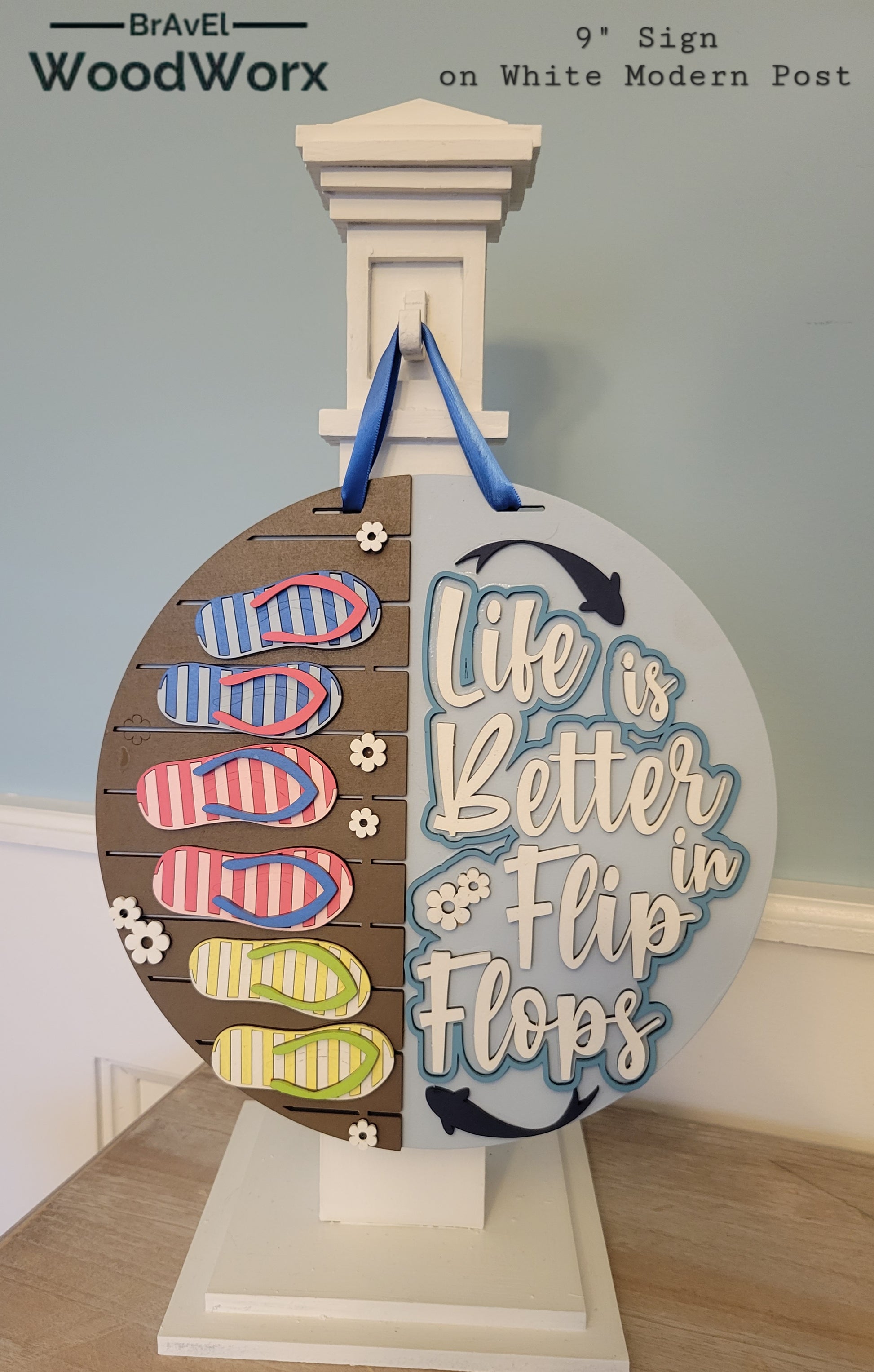 A rectangular wooden sign with a coastal vibe, featuring the text "Life is Better in Flip Flops" written in a playful, beach-inspired font. The background is painted in soft turquoise with a weathered wood texture, accented by illustrations of flip flops and small seashells. Perfect for beach houses, patios, or summer decor. White post