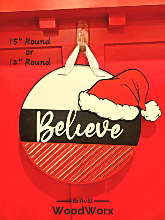 Round wooden Christmas door sign with the word "Believe" and a red Santa hat, hanging on a red background