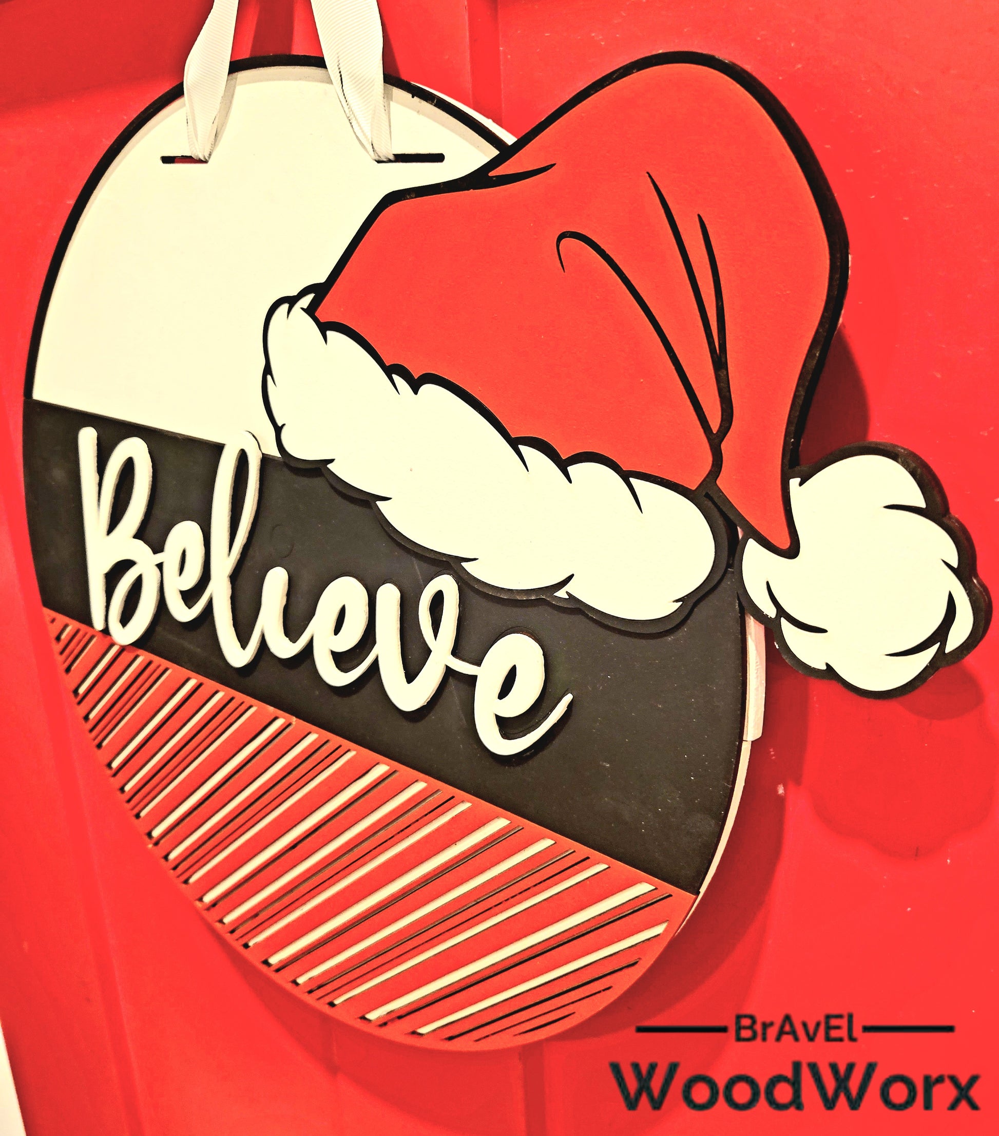 Hand-painted Christmas wall decor featuring a bold "Believe" message and red-and-white striped bottom section