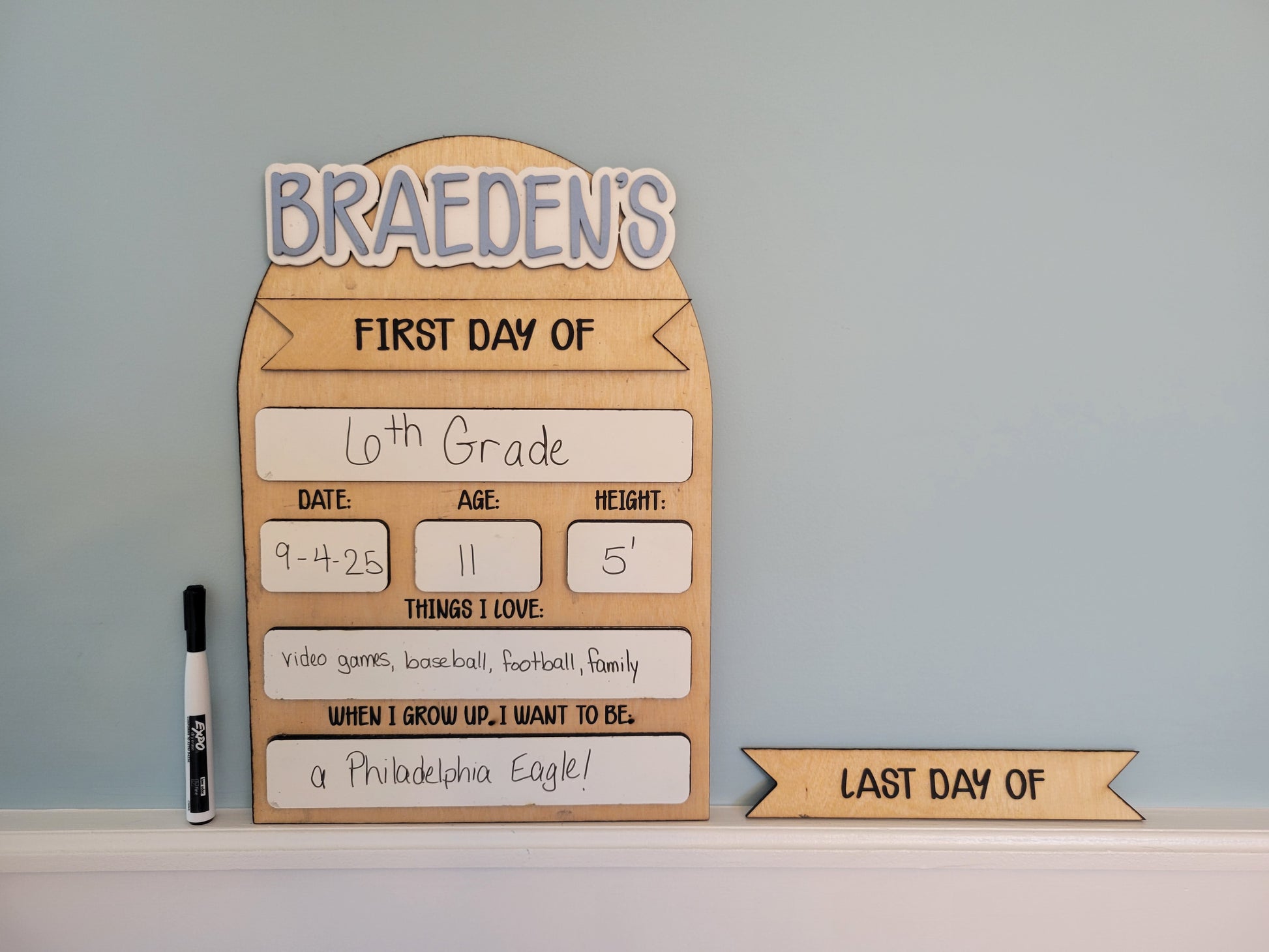 Wooden sign for the first day of school with personal information on a light blue background