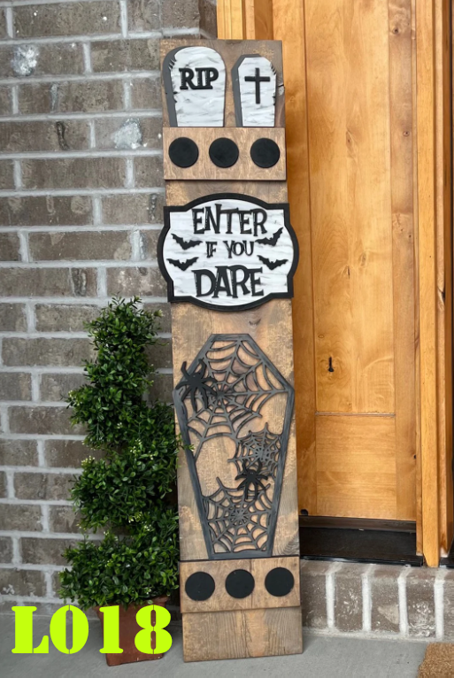 Decorative Halloween sign with tombstones, coffin, and spider web design against a brick wall.