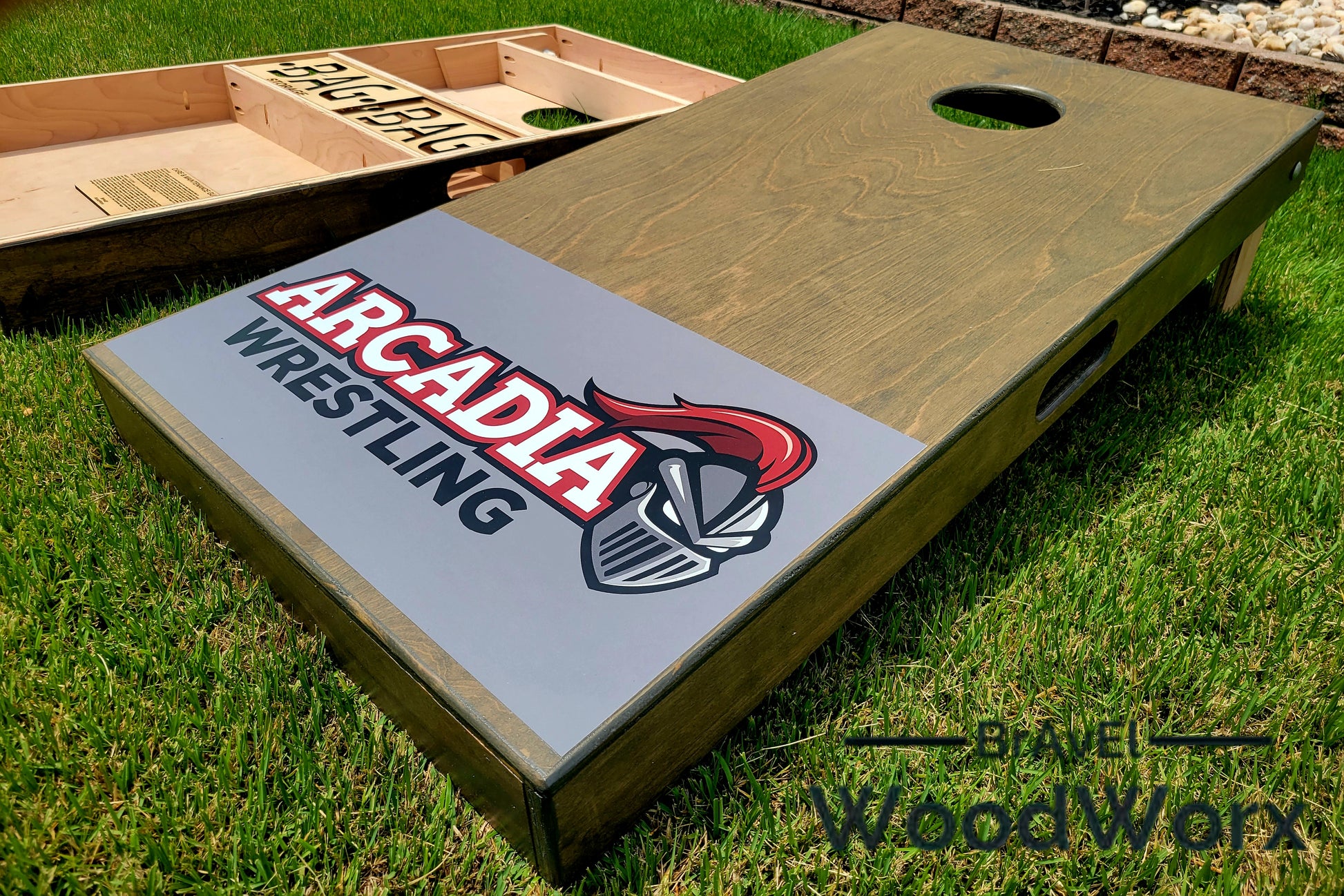 Cornhole board with 'Arcadia Wrestling' design on grass