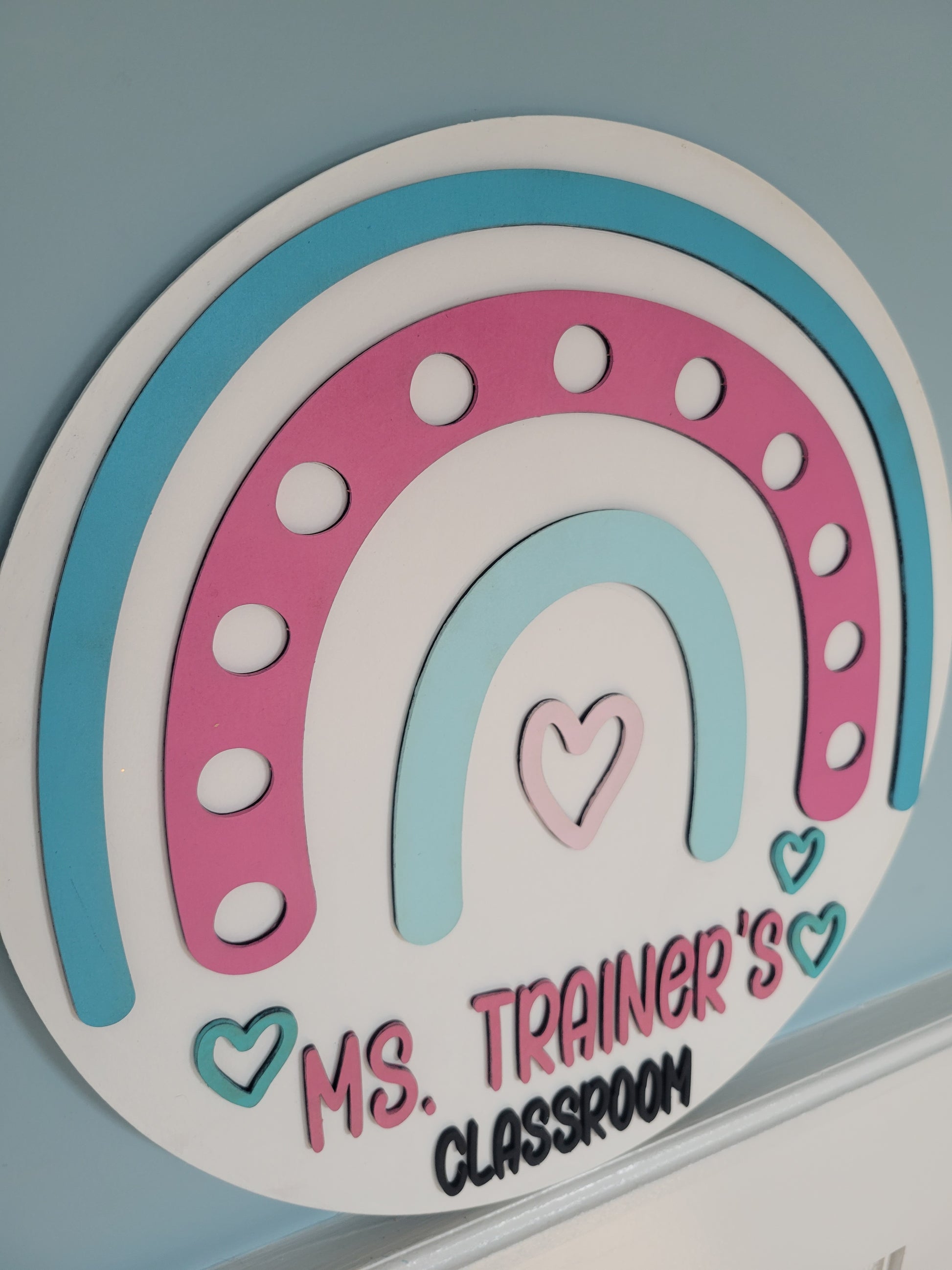 Decorative classroom sign with pink and blue horseshoe design and text on a light gray background