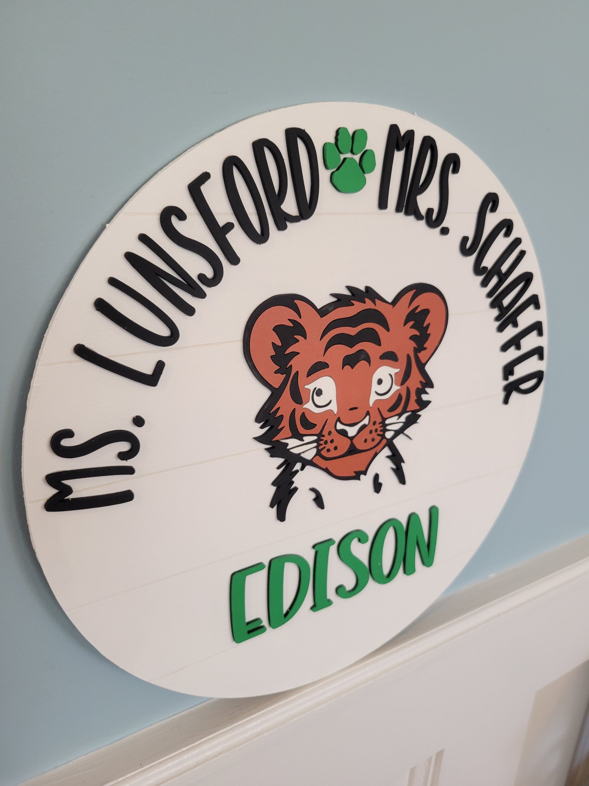 Circular nameplate with tiger illustration and text on a light blue background