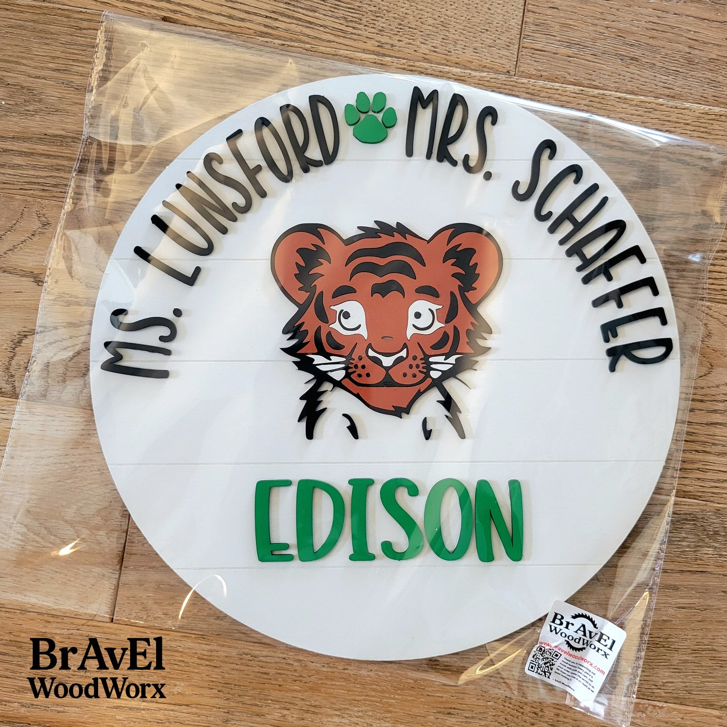 Circular wooden sign with tiger illustration and text on a wooden surface, branded with Bravel WoodWorx.