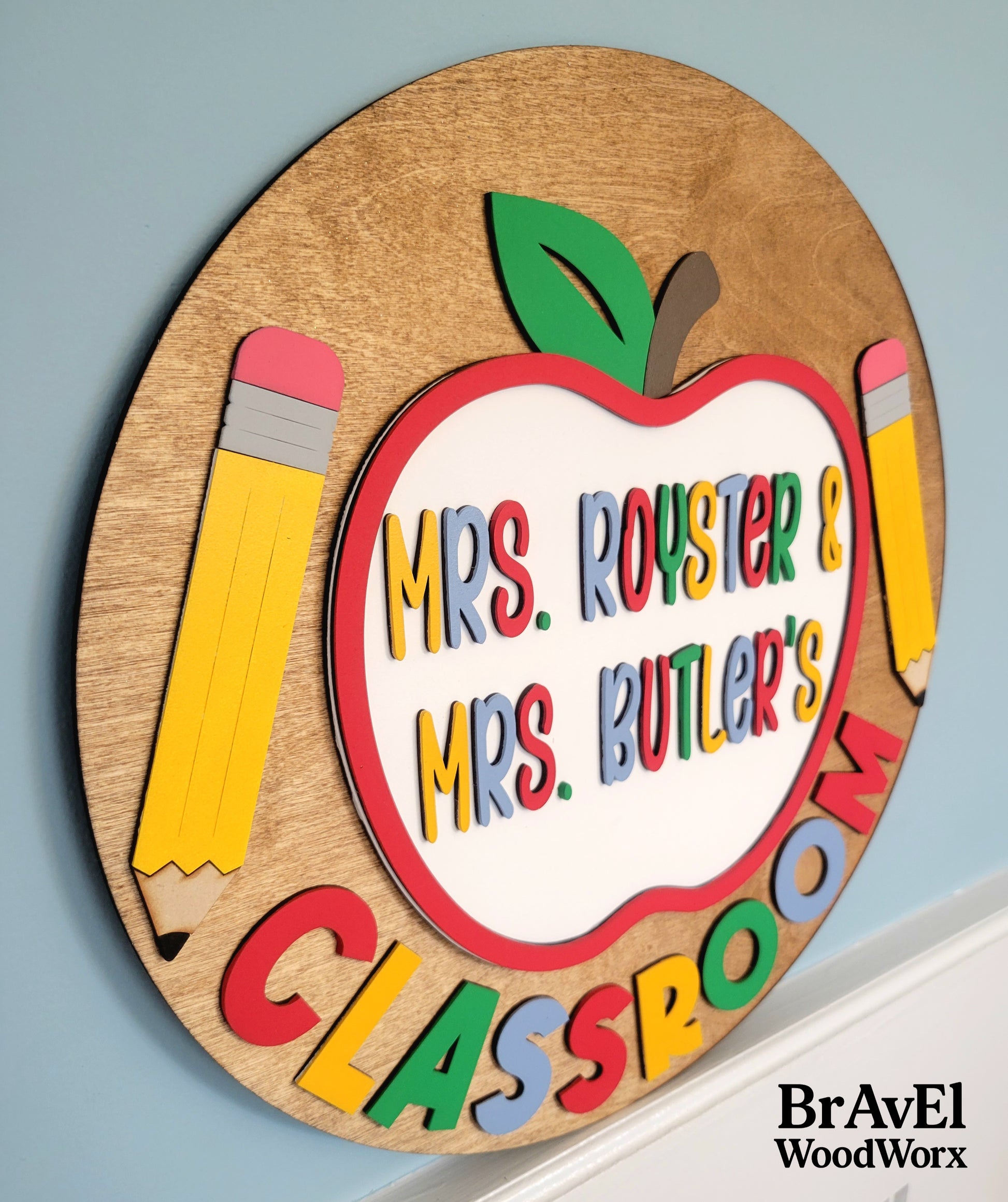 Wooden plaque with colorful text and apple design on a light blue background