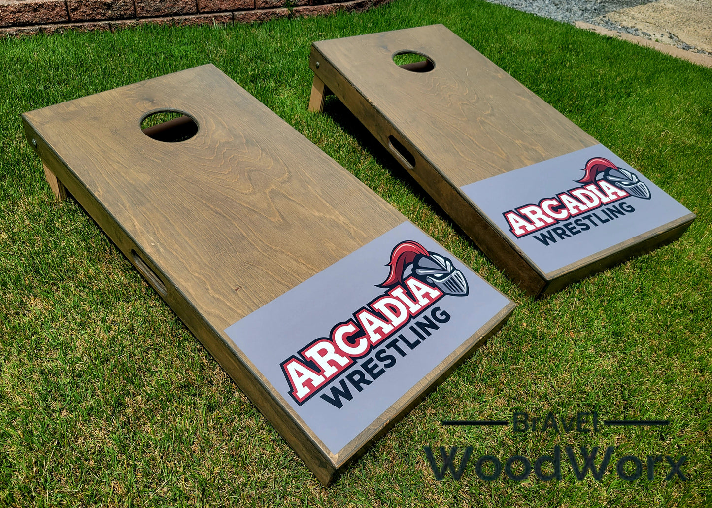 Two wooden cornhole boards with 'Arcadia Wrestling' branding on a grassy background.