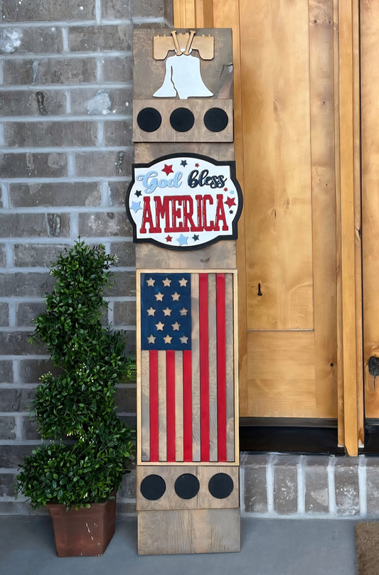 Decorative sign with American flag and 'God Bless America' text against a brick wall.