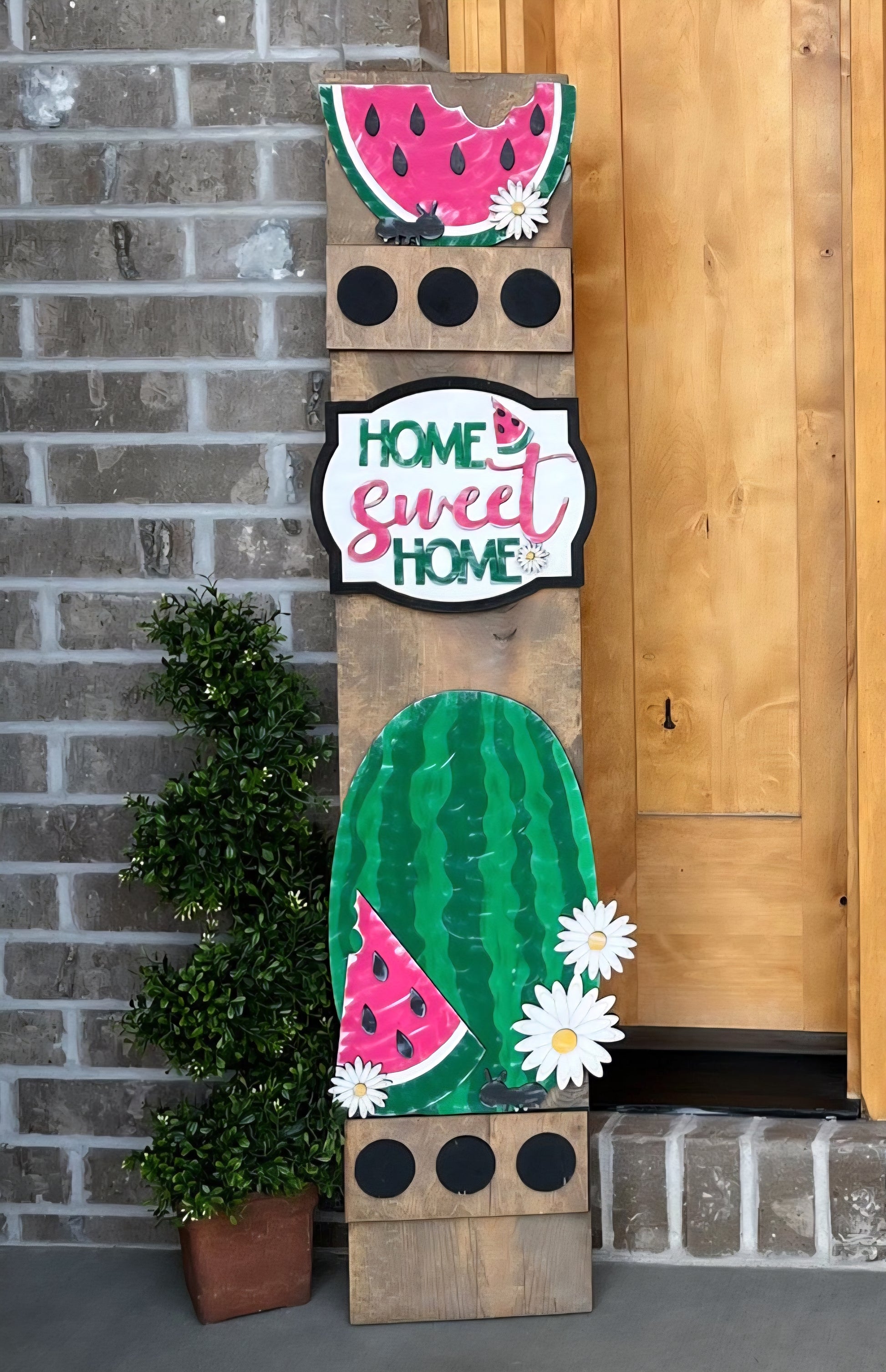 Decorative sign with watermelon design and 'Home Sweet Home' text against a brick wall.